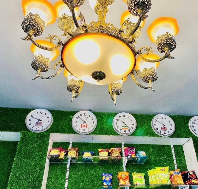 Chandelier above a green wall with world clocks