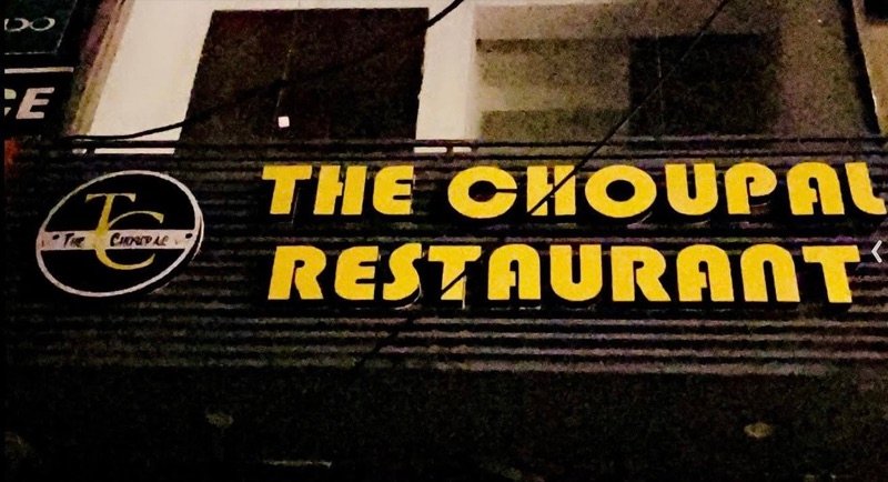 The Choupal Restaurant sign lit up at night